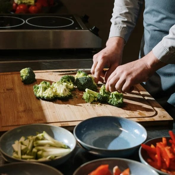 person slicing green vegetables